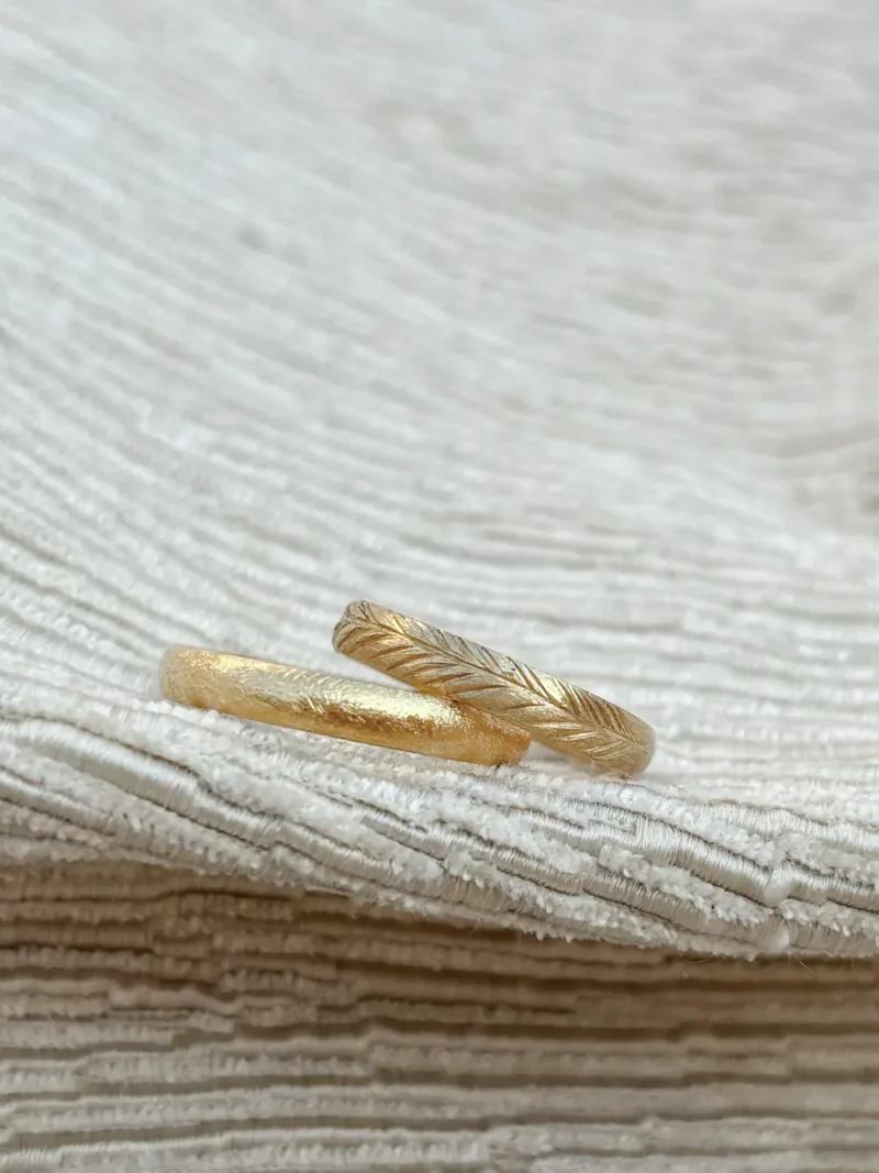 Leuchtend goldenes Ehering Paar mit unterschiedlichen Designs