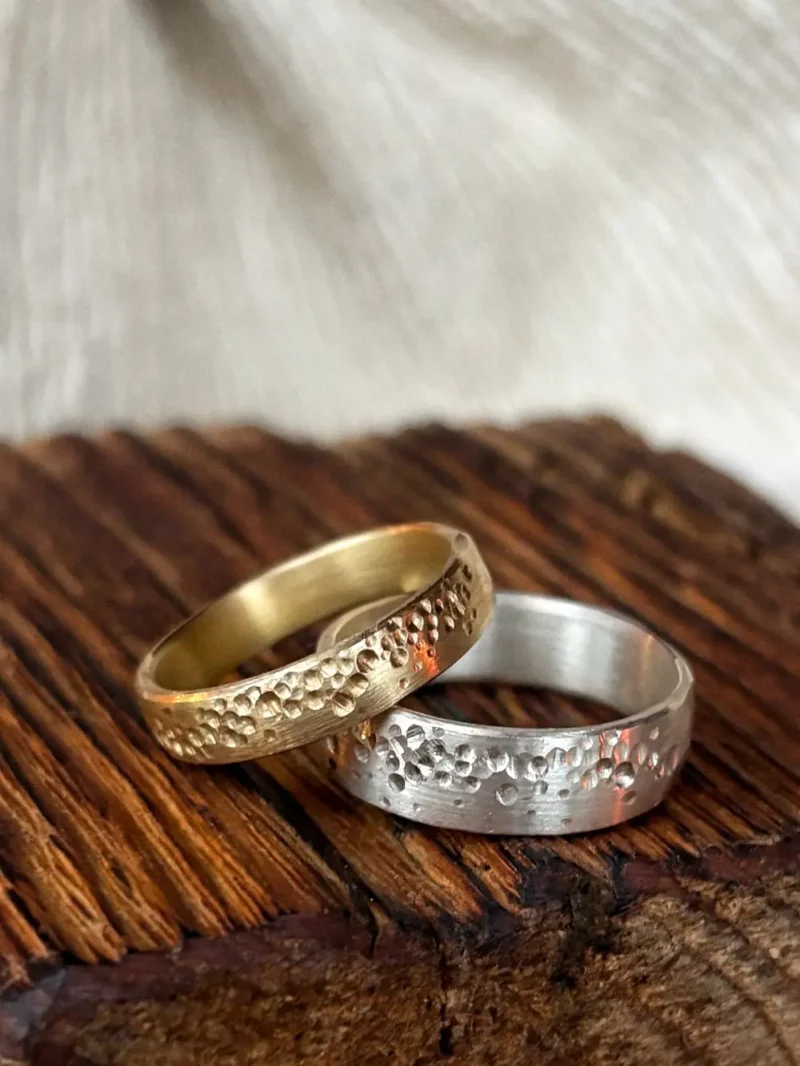 Breite Eheringe in Gelbgold und Platin mit gefrästen Seifenblasen und sanft mattem Grund
