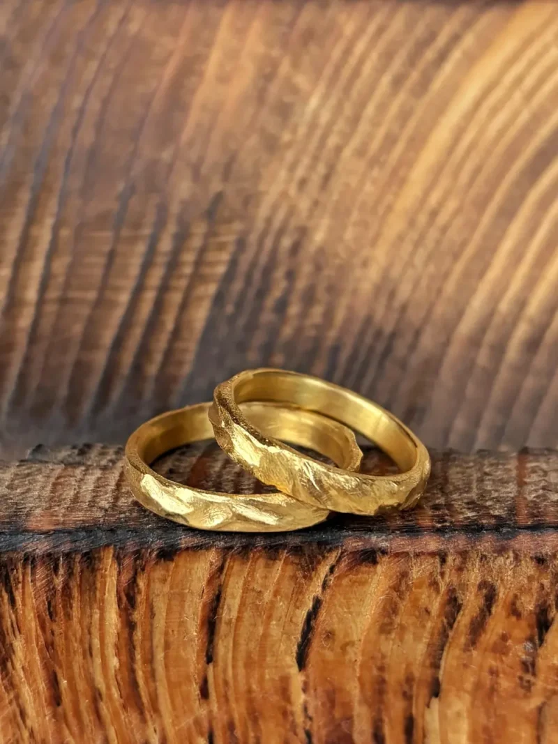 Sattgelbe Gold Eheringe mit starker Struktur auf dunklem Holz