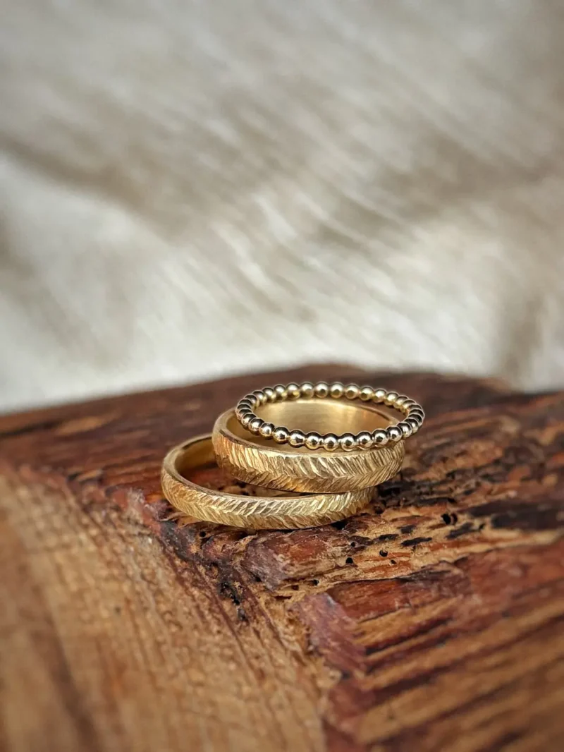 Eheringe mit geschmiedeter, federartiger Oberfläche aus Gelbgold mit kugeligem Vorsteckring