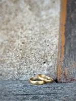 kleine Wellen Eheringe - einzigartige, sanft gefeilte Eheringe aus 750 Gelbgold mit feiner Struktur auf rustikalem Balken