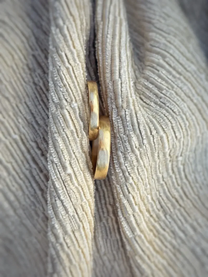 Kleine Wellen Eheringe mit fein gefeilter wellenartiger Oberfläche auf hellem Stoff