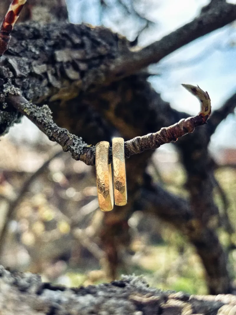 Liebesbrief Eheringe aus 750 Gelbgold mit einzigartiger geschmiedeter Struktur hängen an Ast