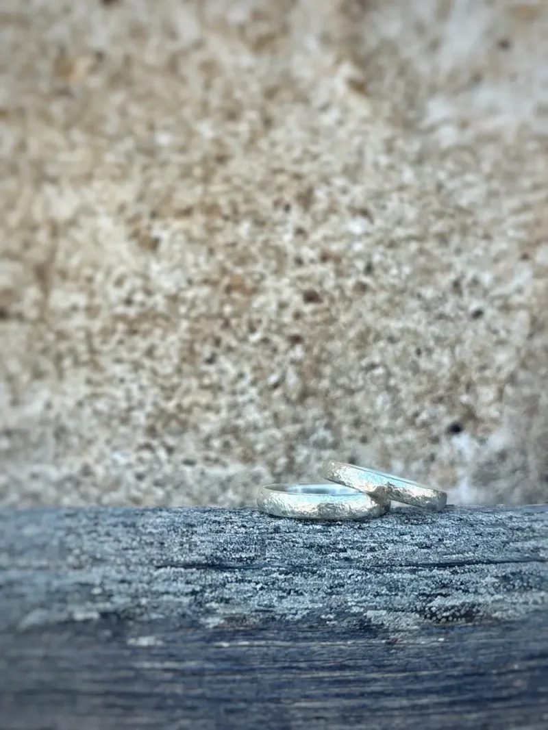 Liebesbrief Eheringe mit einzigartig geschmiedeter Struktur aus Silber auf rustikalem Balken