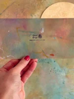 Gutschein Karte künstlerisch bunt gemalt in kräftigen Farben in Hand gehalten