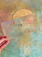 Gutschein Karte künstlerisch bunt gemalt in kräftigen Farben in Hand gehalten