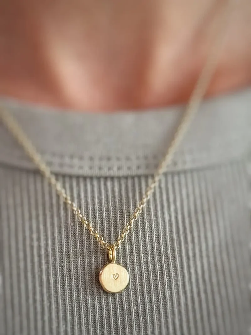 Gestempeltes Herz auf matter Seite von goldenem Kettenanhänger