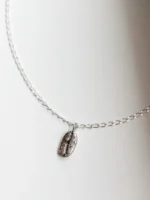 Kaffeebohne aus Silber liegend mit Kette Kaffeebohne aus Silber liegend mit Kette